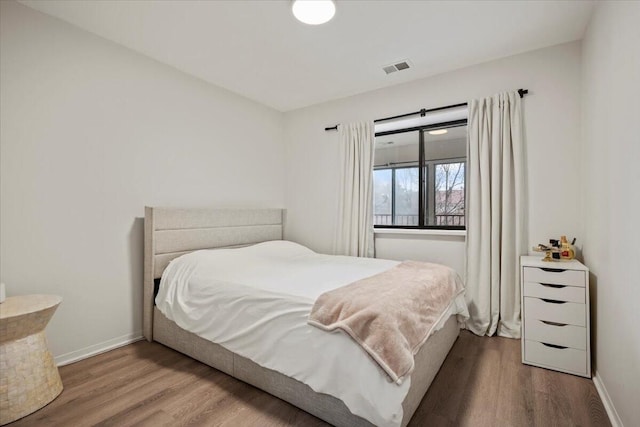 bedroom featuring visible vents, baseboards, and wood finished floors