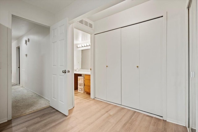 unfurnished bedroom featuring visible vents, baseboards, a closet, connected bathroom, and light wood-style flooring