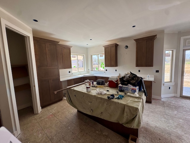 kitchen with crown molding, a center island, light countertops, baseboards, and recessed lighting