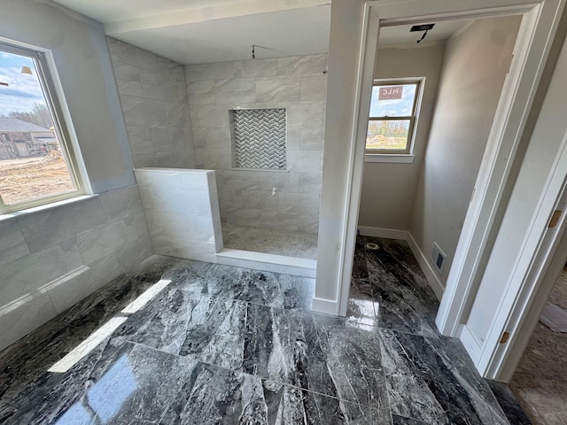 bathroom with baseboards, marble finish floor, and a tile shower