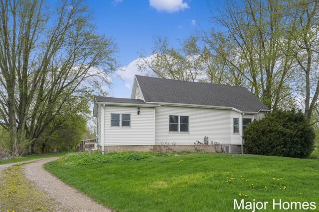 rear view of house with a lawn, central AC unit, and driveway