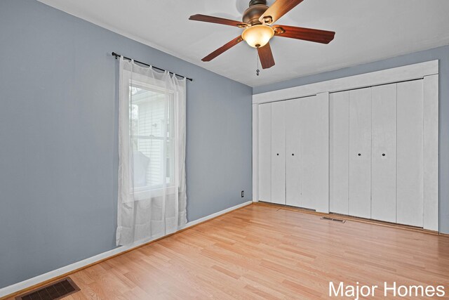 unfurnished bedroom featuring visible vents, baseboards, multiple closets, and wood finished floors