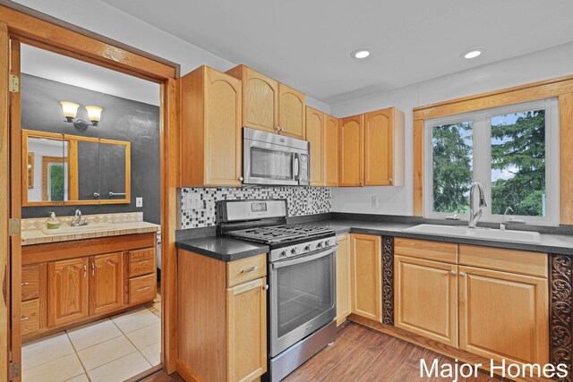 kitchen with a sink, dark countertops, tasteful backsplash, and stainless steel appliances