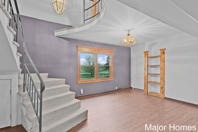 stairway with baseboards, a chandelier, and wood finished floors