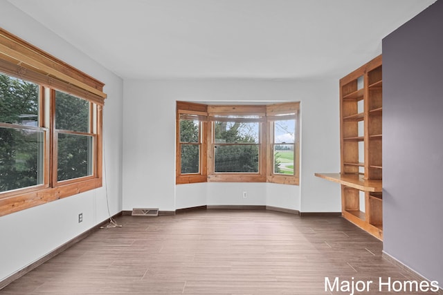 spare room with baseboards, visible vents, and wood finished floors