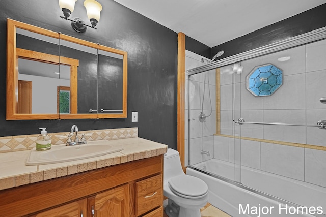 bathroom featuring vanity, enclosed tub / shower combo, and toilet