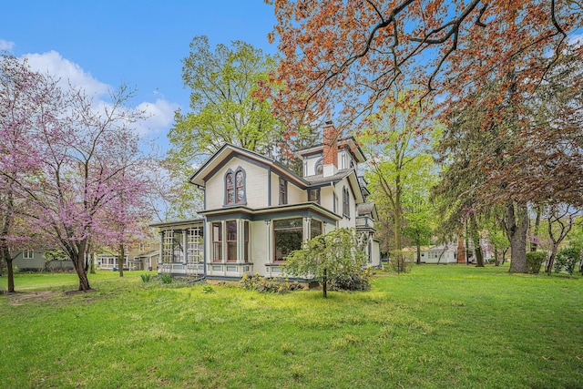 view of side of home with a yard, a chimney, and a sunroom