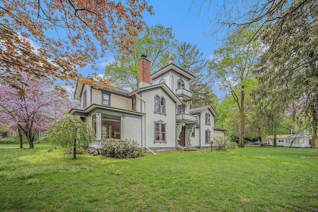 exterior space featuring a chimney, a front lawn, and a balcony
