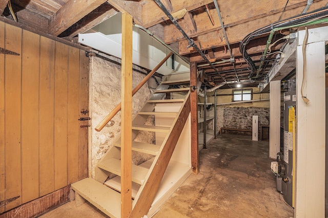 below grade area featuring water heater and wood walls