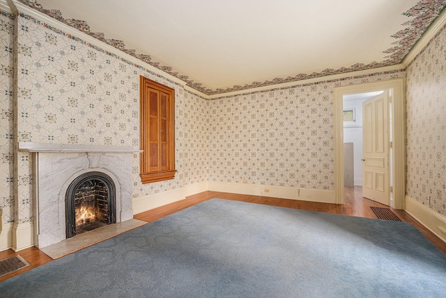 unfurnished living room with wallpapered walls, visible vents, wood finished floors, and a fireplace