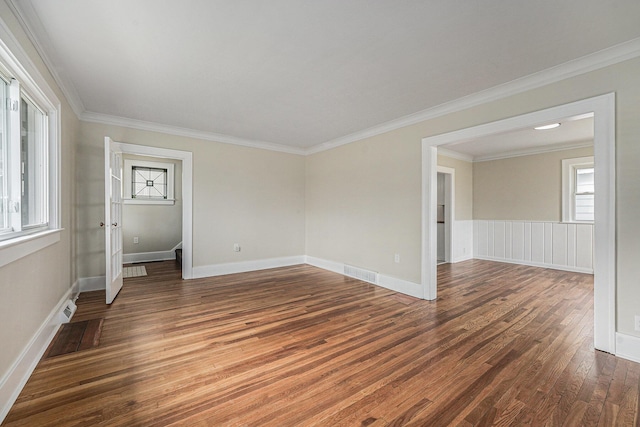 unfurnished room featuring crown molding, baseboards, wood finished floors, and visible vents