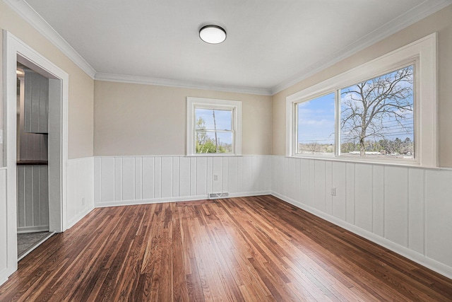 empty room featuring visible vents, a wainscoted wall, and hardwood / wood-style floors