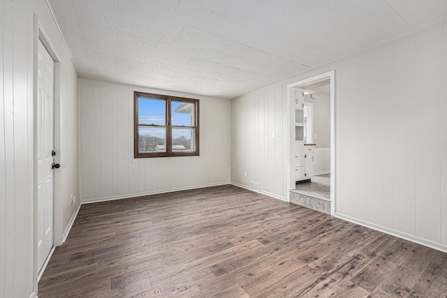 unfurnished bedroom with baseboards, connected bathroom, wood finished floors, and visible vents
