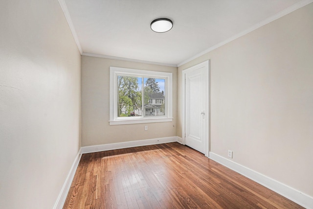 empty room featuring crown molding, baseboards, and hardwood / wood-style floors