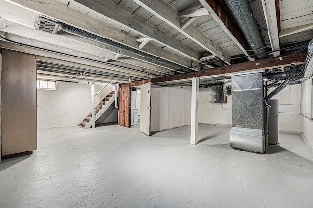 basement with heating unit, electric panel, stairs, and visible vents