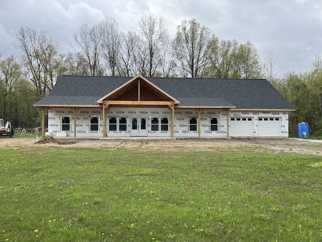 property in mid-construction with covered porch, an attached garage, driveway, and a front lawn