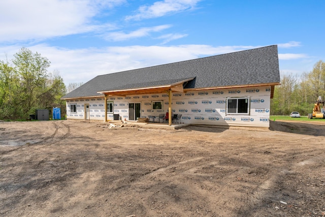 rear view of property featuring a shingled roof and an attached garage