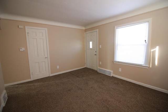 foyer featuring baseboards, visible vents, and dark carpet