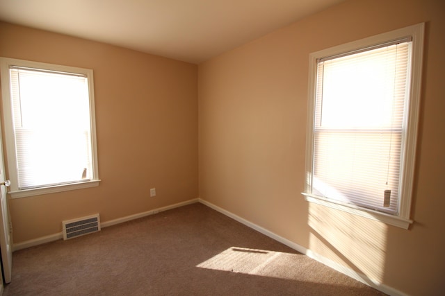 empty room featuring carpet floors, baseboards, and visible vents