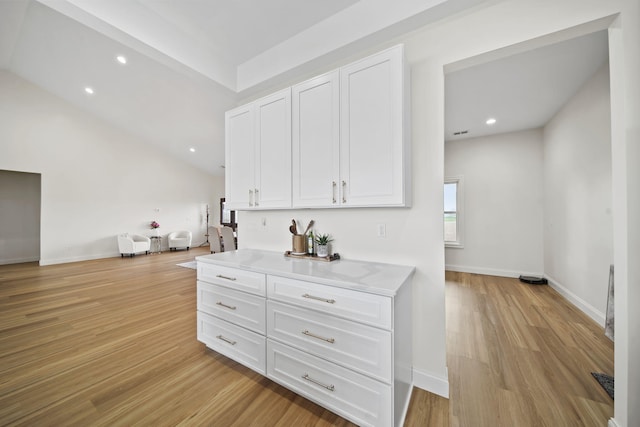 interior space featuring white cabinets, light countertops, open floor plan, baseboards, and light wood-type flooring