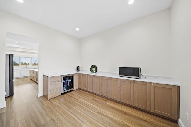 bar featuring a dry bar, freestanding refrigerator, beverage cooler, light wood-style floors, and recessed lighting