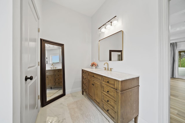 bathroom with vanity, marble finish floor, and baseboards