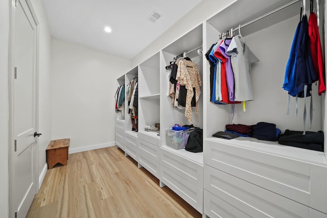walk in closet with light wood-style floors