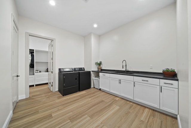 kitchen featuring light wood-style floors, a sink, washer and dryer, and dark countertops