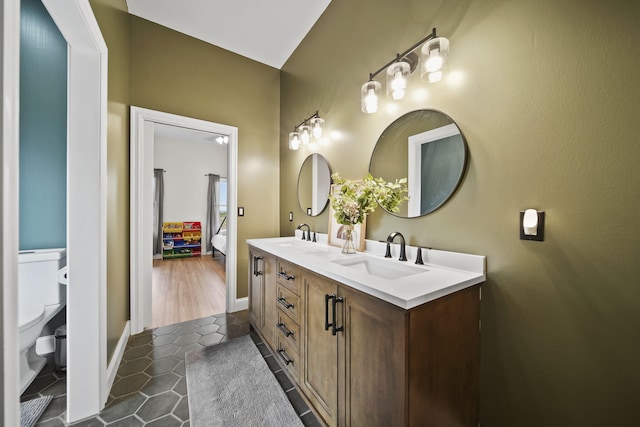full bath with double vanity, tile patterned flooring, a sink, toilet, and connected bathroom