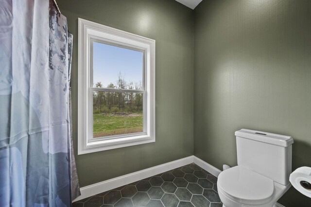 bathroom with baseboards, tile patterned floors, and a healthy amount of sunlight