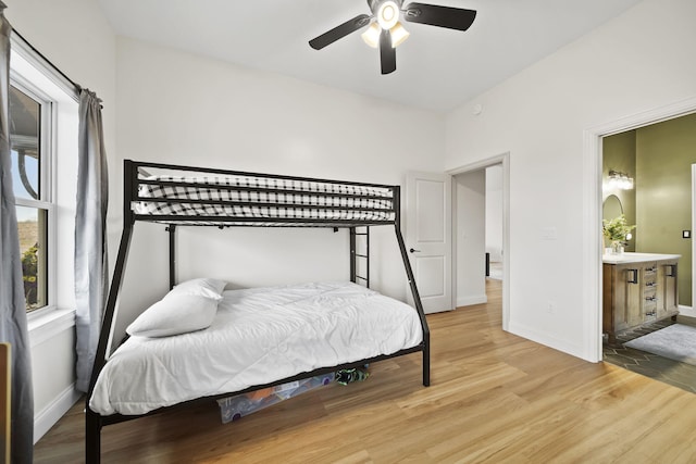 bedroom with a ceiling fan, baseboards, ensuite bathroom, and light wood-type flooring