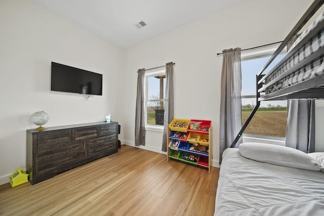 bedroom with baseboards, wood finished floors, and visible vents