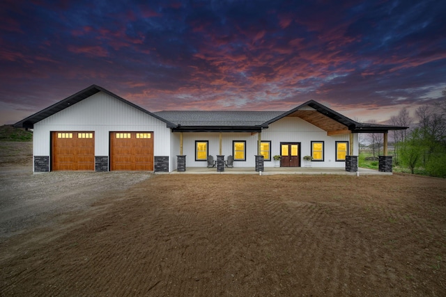 view of front of house featuring driveway, a shingled roof, stone siding, and a garage