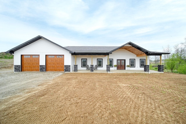 modern farmhouse style home with driveway, french doors, stone siding, and a garage