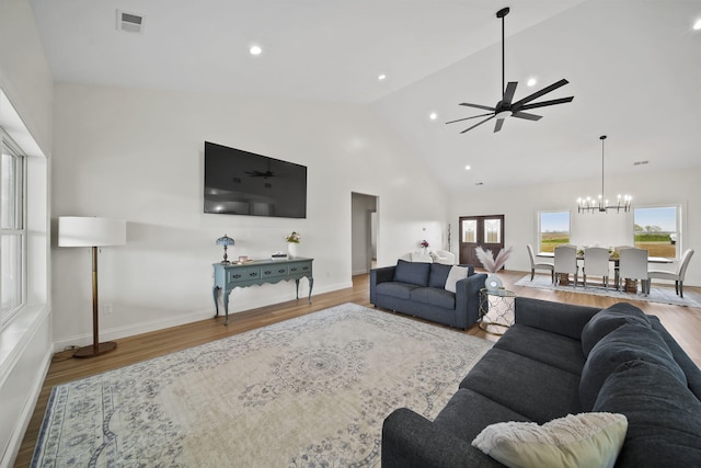 living area with baseboards, ceiling fan with notable chandelier, wood finished floors, and visible vents