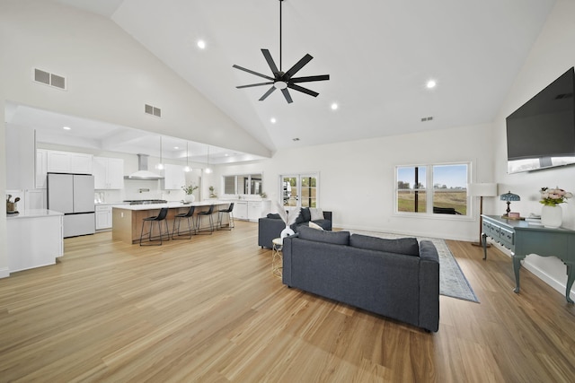 living room with high vaulted ceiling, a ceiling fan, light wood-type flooring, and visible vents