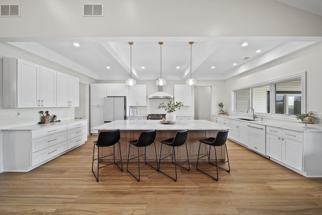 kitchen featuring visible vents, freestanding refrigerator, a breakfast bar area, a sink, and dishwasher