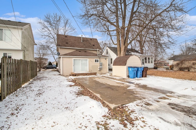 snow covered property featuring a storage unit, fence, and an outbuilding