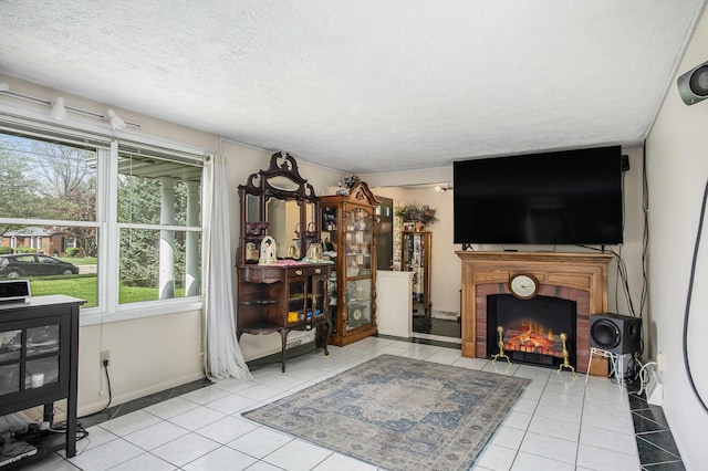 living room featuring a healthy amount of sunlight, tile patterned flooring, a brick fireplace, and a textured ceiling