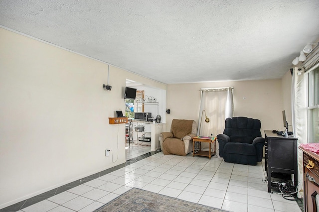 sitting room with light tile patterned floors, baseboards, and a textured ceiling