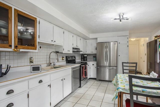 kitchen featuring decorative backsplash, a sink, under cabinet range hood, stainless steel appliances, and light tile patterned flooring
