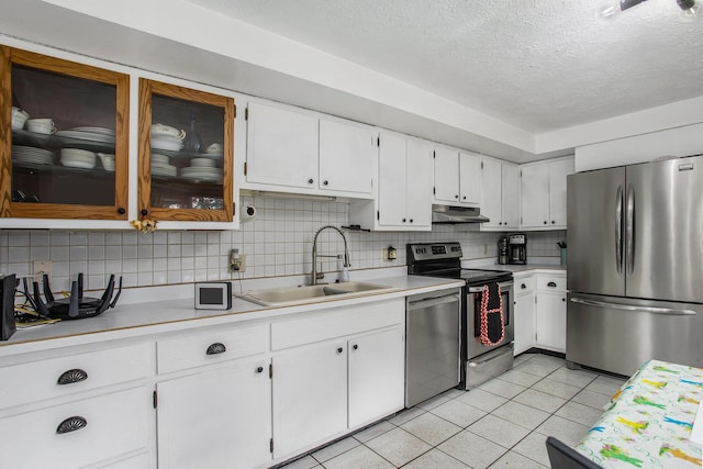 kitchen featuring appliances with stainless steel finishes, a sink, light tile patterned floors, light countertops, and under cabinet range hood