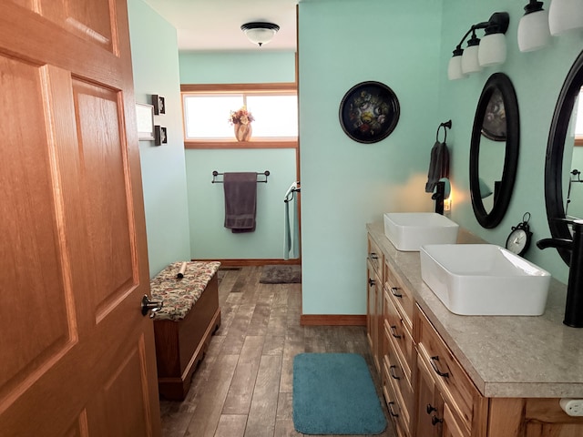 full bathroom with a sink, baseboards, double vanity, and hardwood / wood-style floors