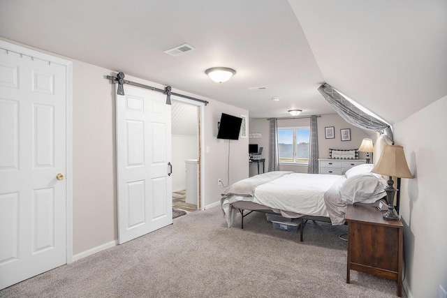 carpeted bedroom featuring baseboards, a barn door, and visible vents