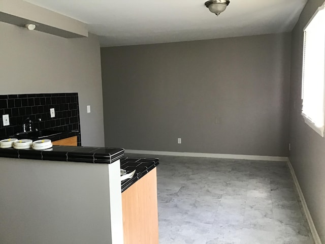 23822 Wellington Ave, Warren, MI 48089 - kitchen featuring concrete flooring, tile countertops, baseboards, a peninsula, and tasteful backsplash
