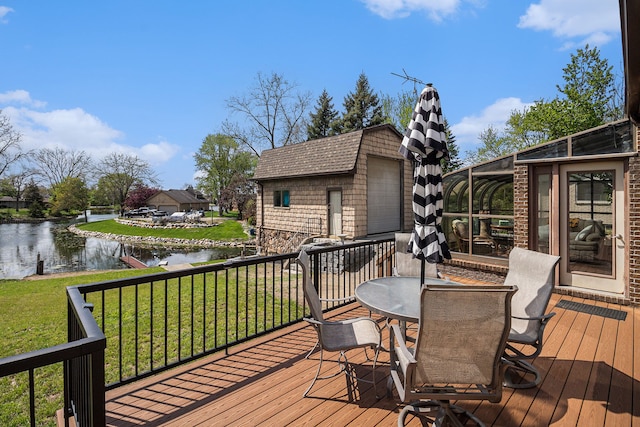 deck with a water view, a yard, outdoor dining space, and a detached garage