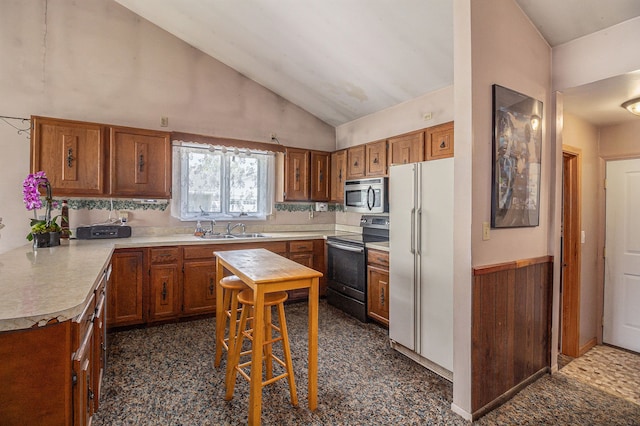 kitchen with stainless steel appliances, a sink, light countertops, brown cabinetry, and lofted ceiling