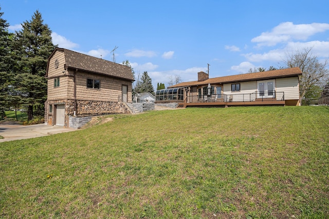 view of green lawn with a deck, a garage, and concrete driveway