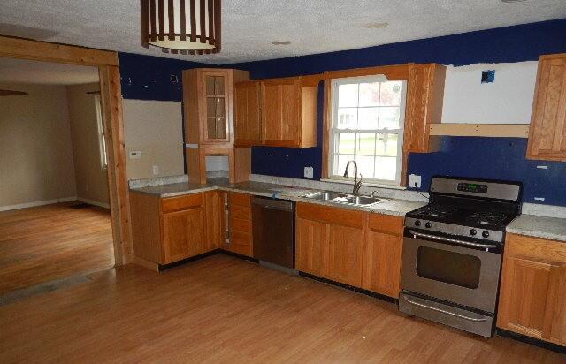 kitchen with dishwasher, a sink, light countertops, stainless steel range with gas cooktop, and light wood-style flooring