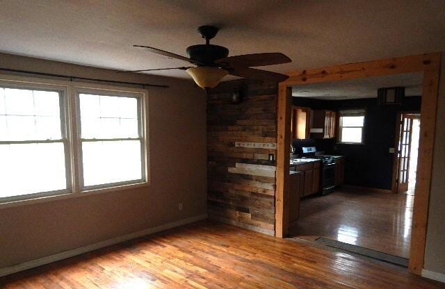 spare room featuring baseboards, a ceiling fan, and light wood-style flooring